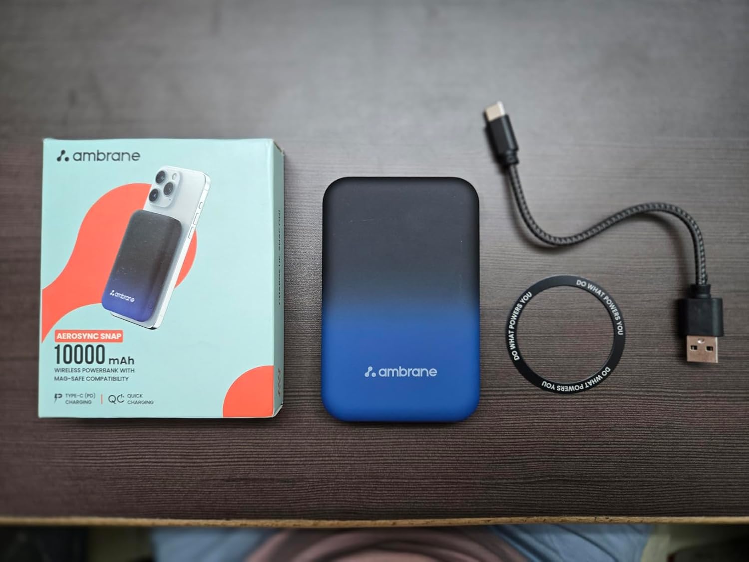 Ambrane AeroSync Snap top view in hand for scale, showing rubberised matte finish, USB-A and USB-C ports along the edge