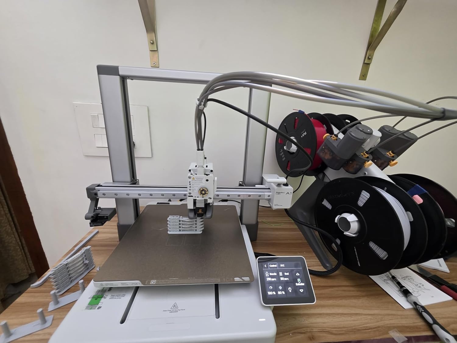 Bambu Lab A1 Combo unboxing photo showing the printer base, AMS Lite unit, mounting arm, textured PEI build plate and accessories laid out from a verified Amazon.in customer order