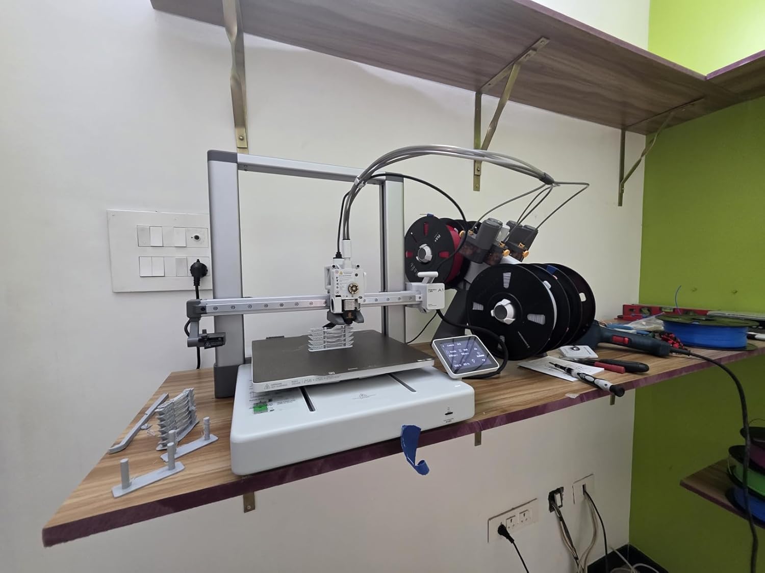 Bambu Lab A1 Combo set up on a desk in real-world use with the AMS Lite mounted to the right of the printer and the textured PEI build plate visible