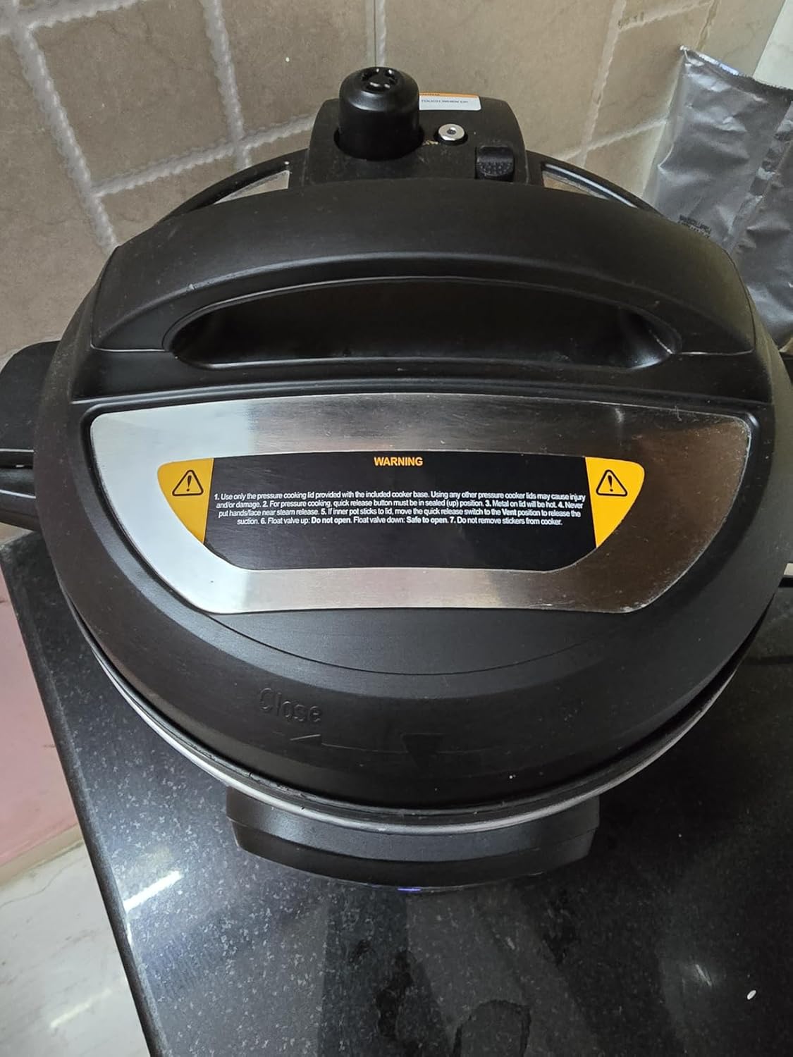 Top-down view of the Instant Pot Duo lid showing the steam release valve, quick-release toggle and the printed safety warning label around the float valve