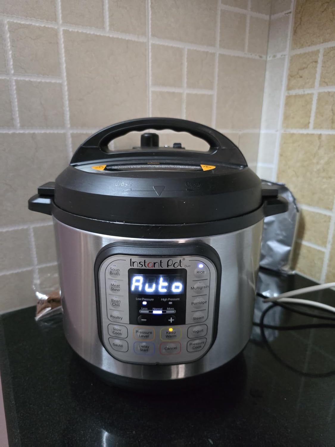 Instant Pot Duo Indian variant running on a granite kitchen counter with the LED display showing Auto and the 230V power cable plugged in to the rear
