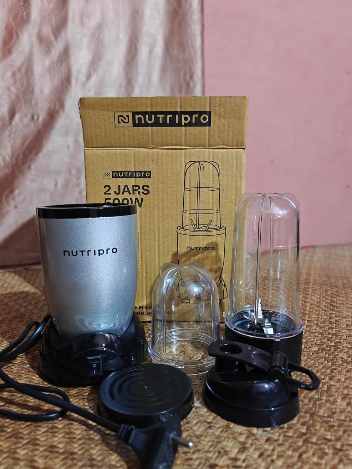 NutriPro Juicer Mixer Grinder 500W lifestyle shot showing the appliance in a typical Indian kitchen with the sipper jar mounted, the stainless-steel chutney jar on the counter and the multi-purpose blade unit visible