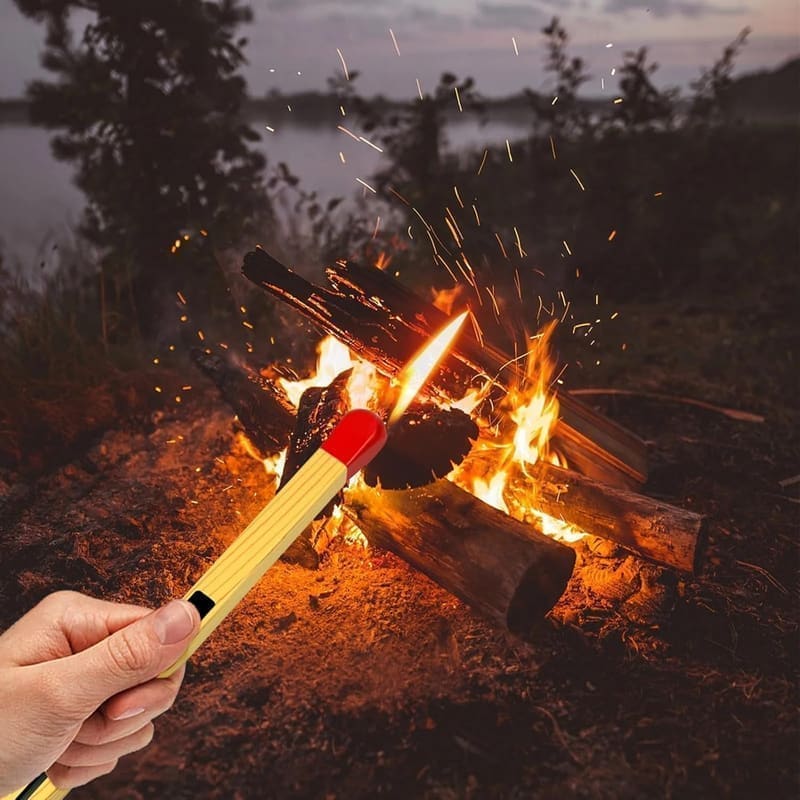 Sajani long-handle gas lighter in use lighting a kitchen stove burner with a clean blue flame extending from the tip, showing the arm's-length safe distance from the burner