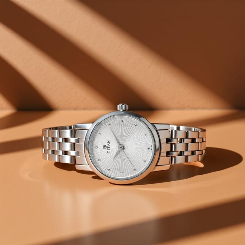 Titan NT2593SM01 lying on a tan surface in warm light showing the polished steel bracelet